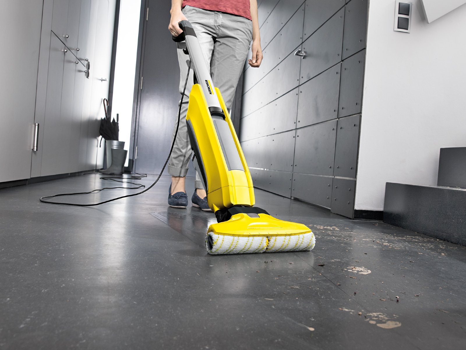 Person reinigt Boden mit elektrischem Reinigungsgerät